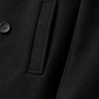 Close-up of black peacoat side pocket and fabric detail